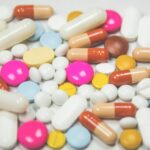 Tablets and capsules in many colors and shapes, including pink, blue, yellow and white pills, on a white surface